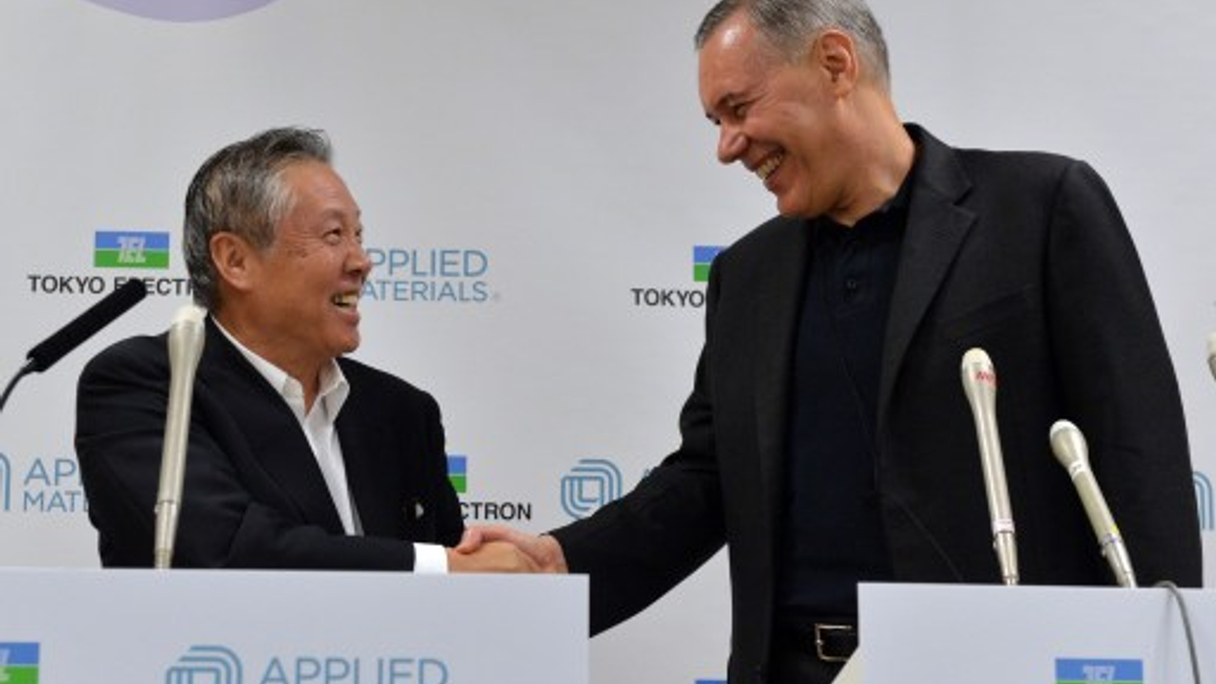 Tetsuro Higashi, chairman of Tokyo Electron, and  Gary Dickerson, president and chief executive of Applied Materials, shake hands during the unveiling of the deal.