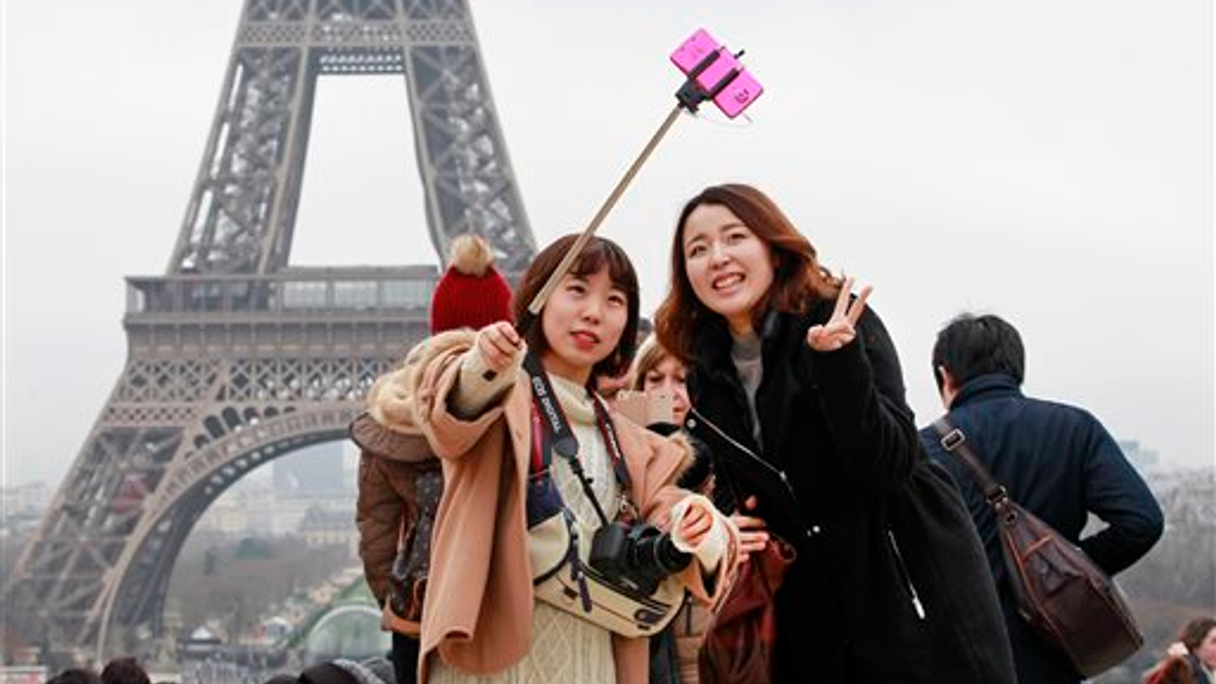 Chinese tourists take a selfie in front of Eiffel Tower in Paris, France.