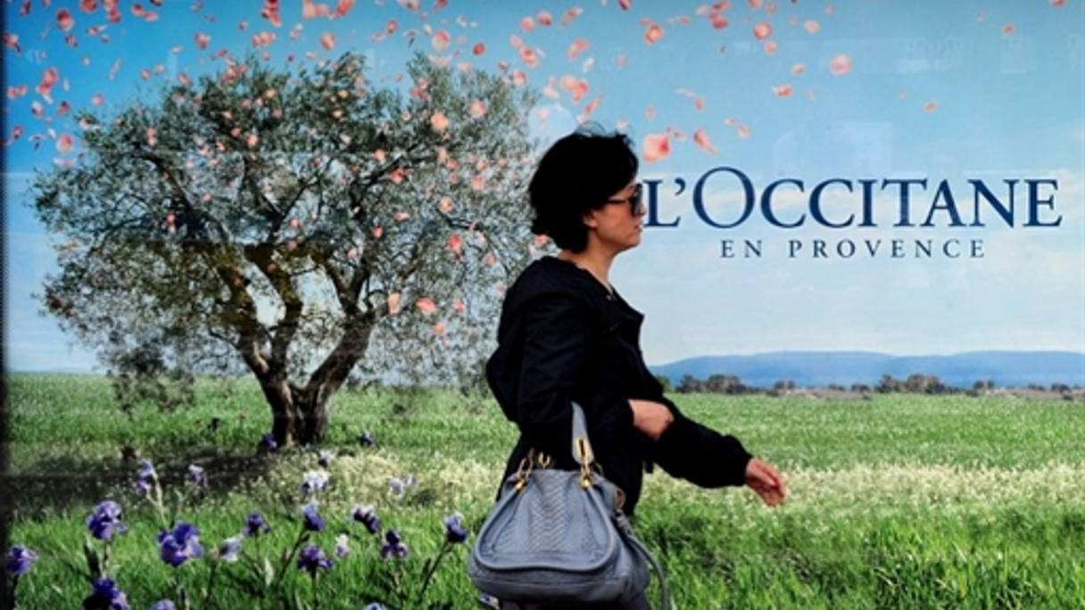 A woman walks past one of numerous L'Occitane ads in Hong Kong as the French brand prepares to list on the Hong Kong bourse.