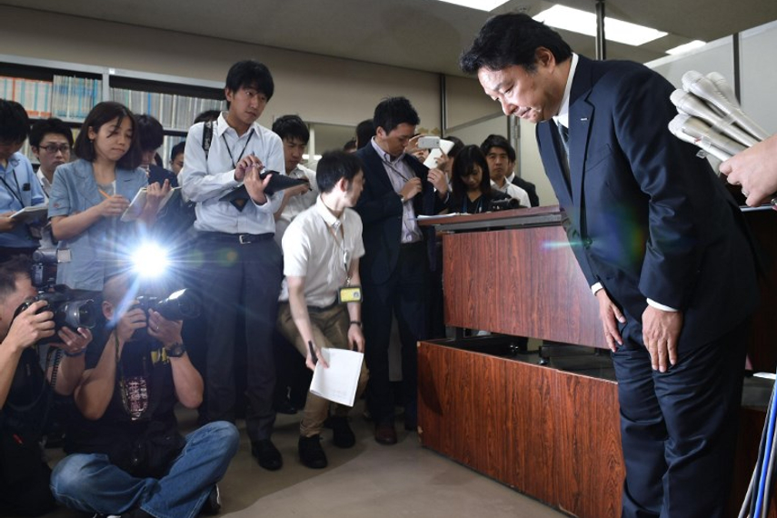 記者会見で頭を下げる山本敏博・電通社長